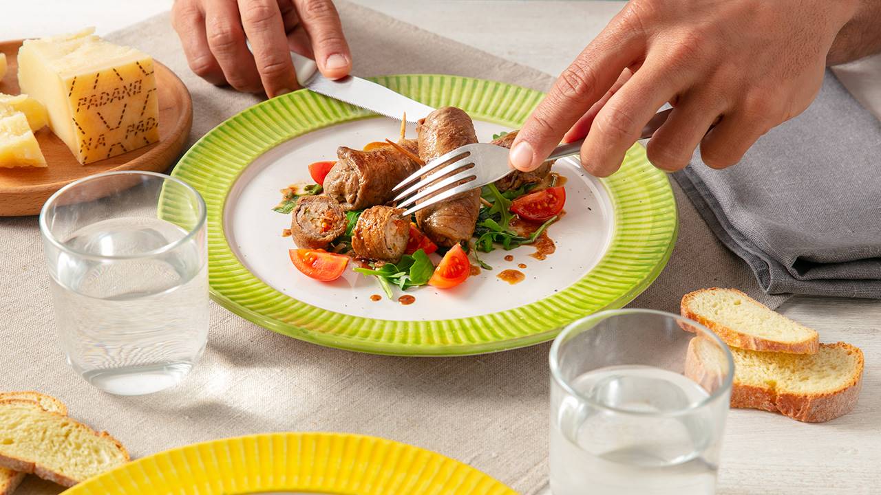 Pan-cooked beef rolls filled with prosciutto crudo, fresh tomatoes, Grana Padano and rocket