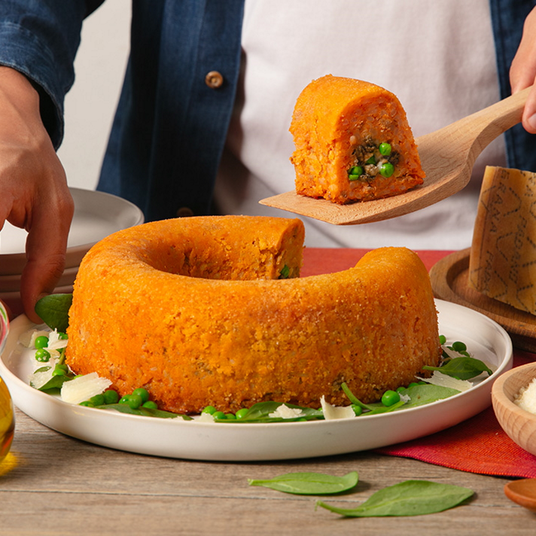 Timballo di riso al sugo di pomodoro, ripieno di ragù bianco di piselli e Grana Padano