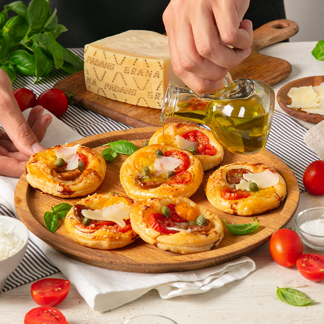 Small puff pastry pizzas with red and yellow grape tomatoes, capers and Grana Padano