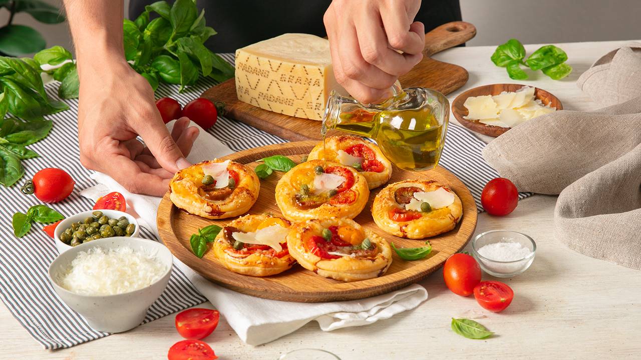 Pizzette aus Blätterteig mit roten und gelben Datteltomaten, Kapern und Grana Padano