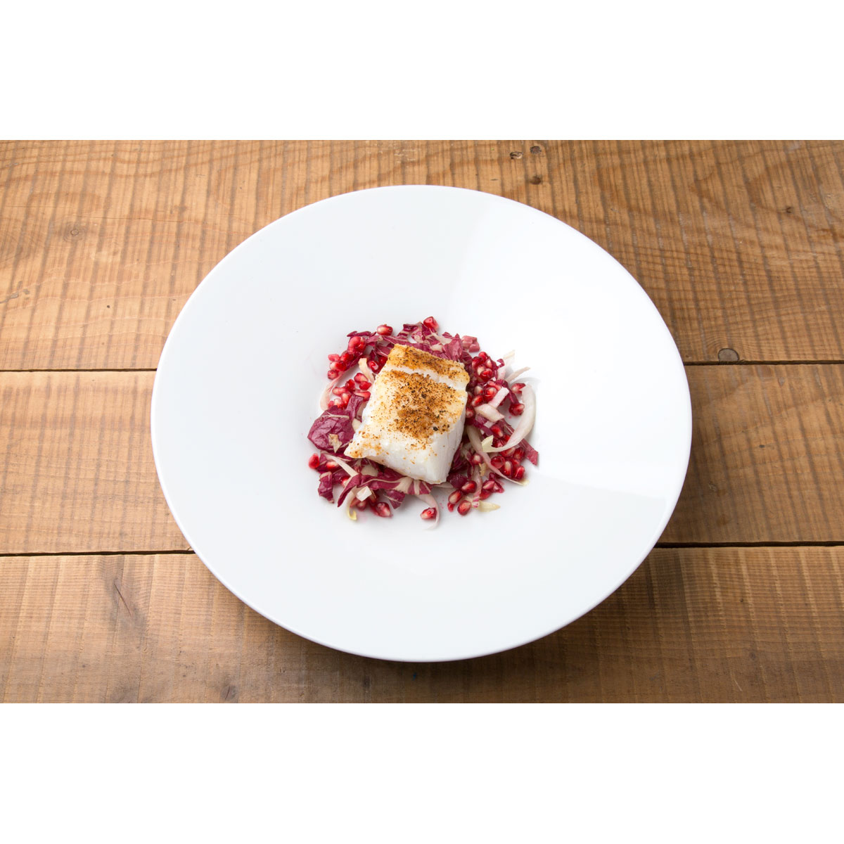 Filetto di baccalà gratinato al panettone e Grana Padano, insalata di indivia e melagrana