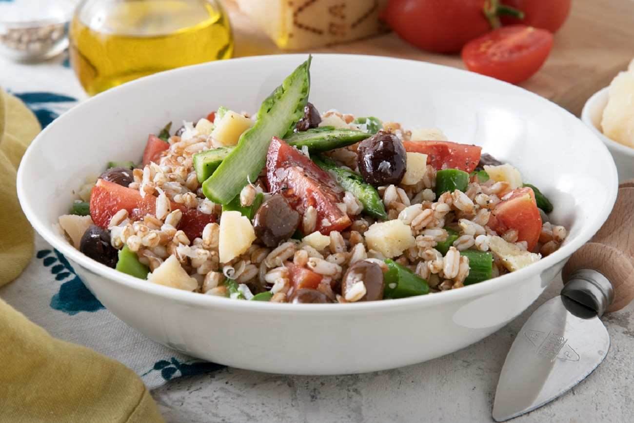 Salat mit Dinkel, frischen Tomaten, Rucola, Spargel, Taggiasche-Oliven und dünn gehobelten Grana Padano