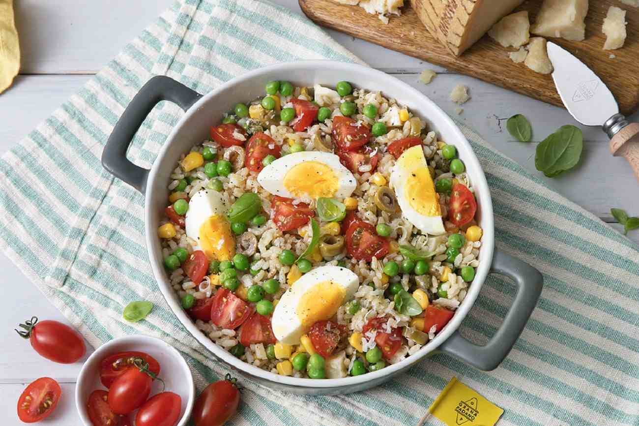 Vollkornreissalat mit Erbsen, Cocktailtomaten, gekochten Eiern, grünen Oliven, Mais, Basilikum und Grana Padano DOP