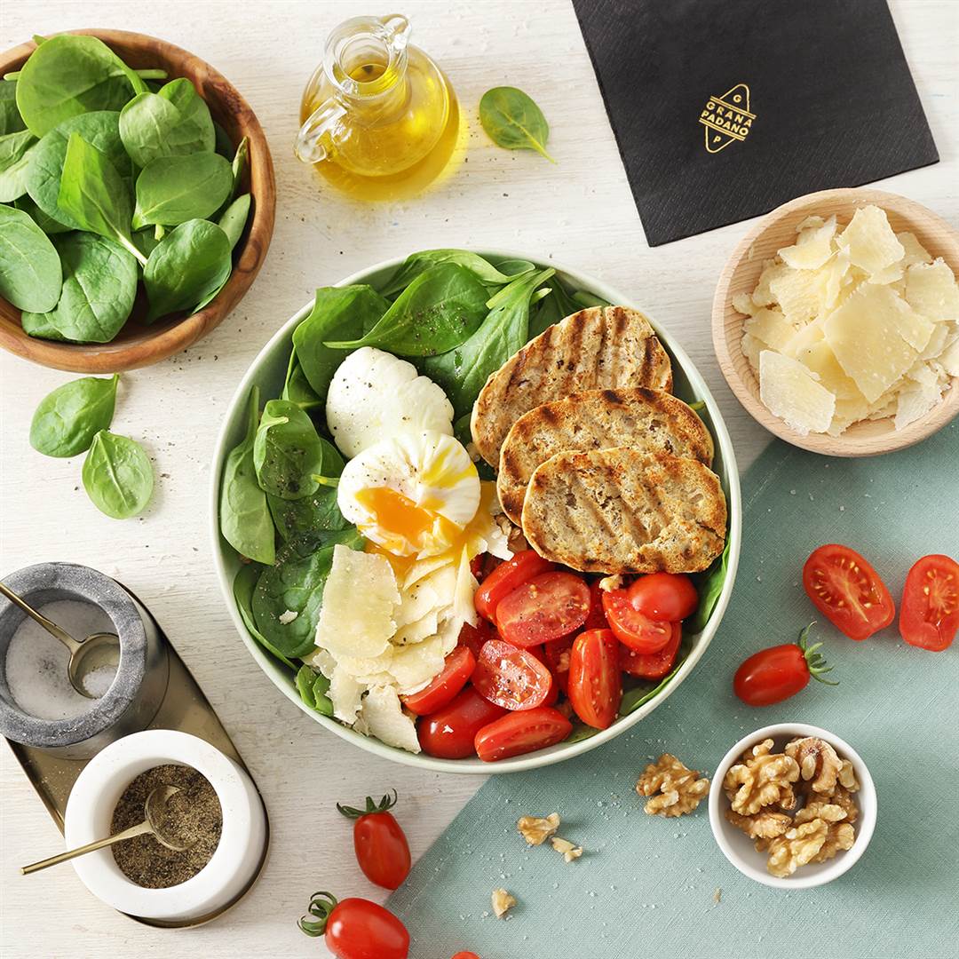 Spinatsalat, geröstetes 5-Korn-Brot, pochiertes Ei, Walnusskerne, Datteltomaten und Grana Padano-Splitter