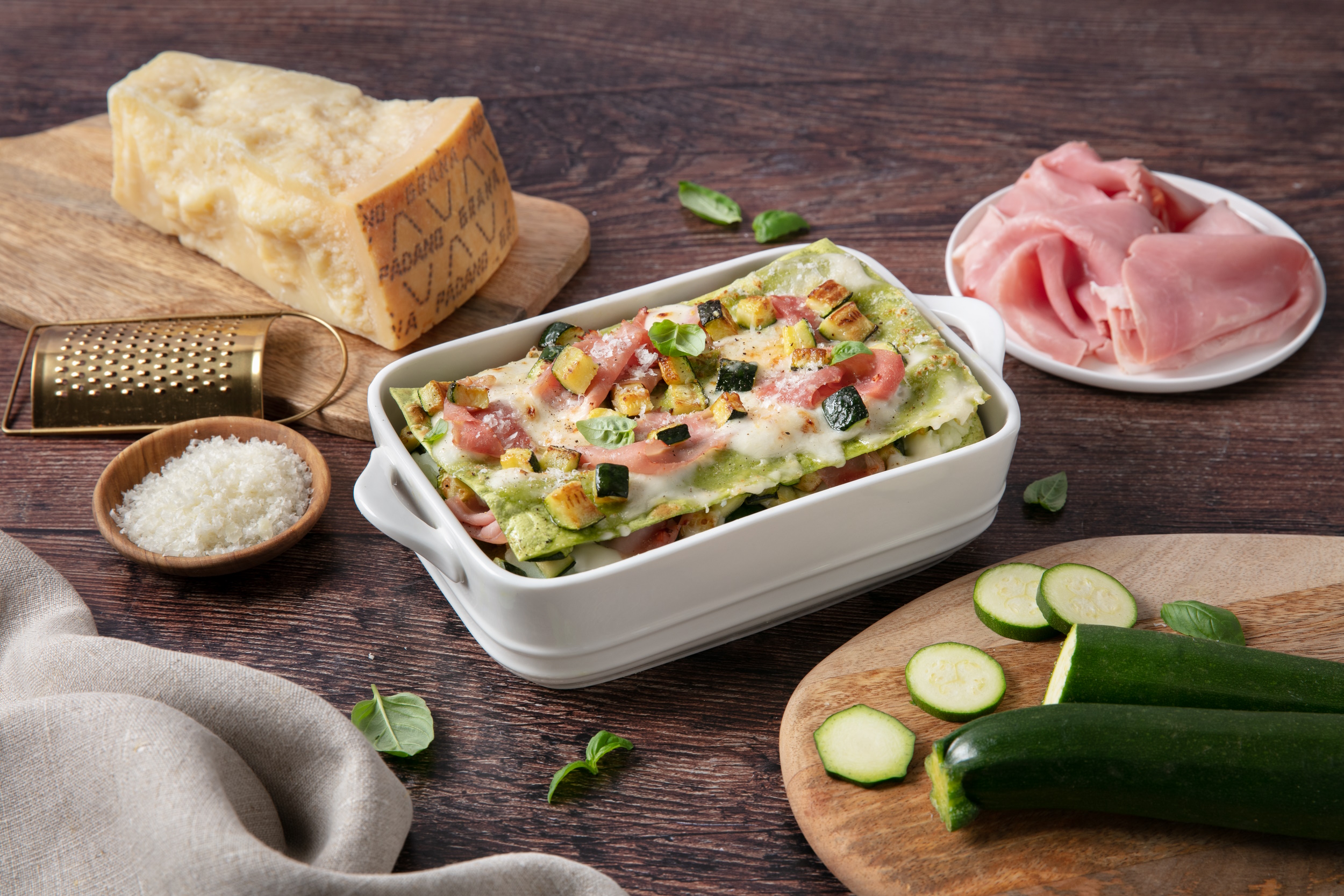 Green lasagne with bechamel sauce, courgettes, ham, and Grana Padano