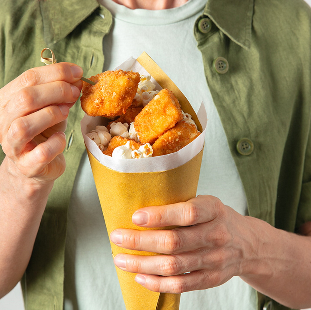 Frittierte Hähnchenstücke, mit Popcorn und Grana Padano in der Pergamentpapiertüte