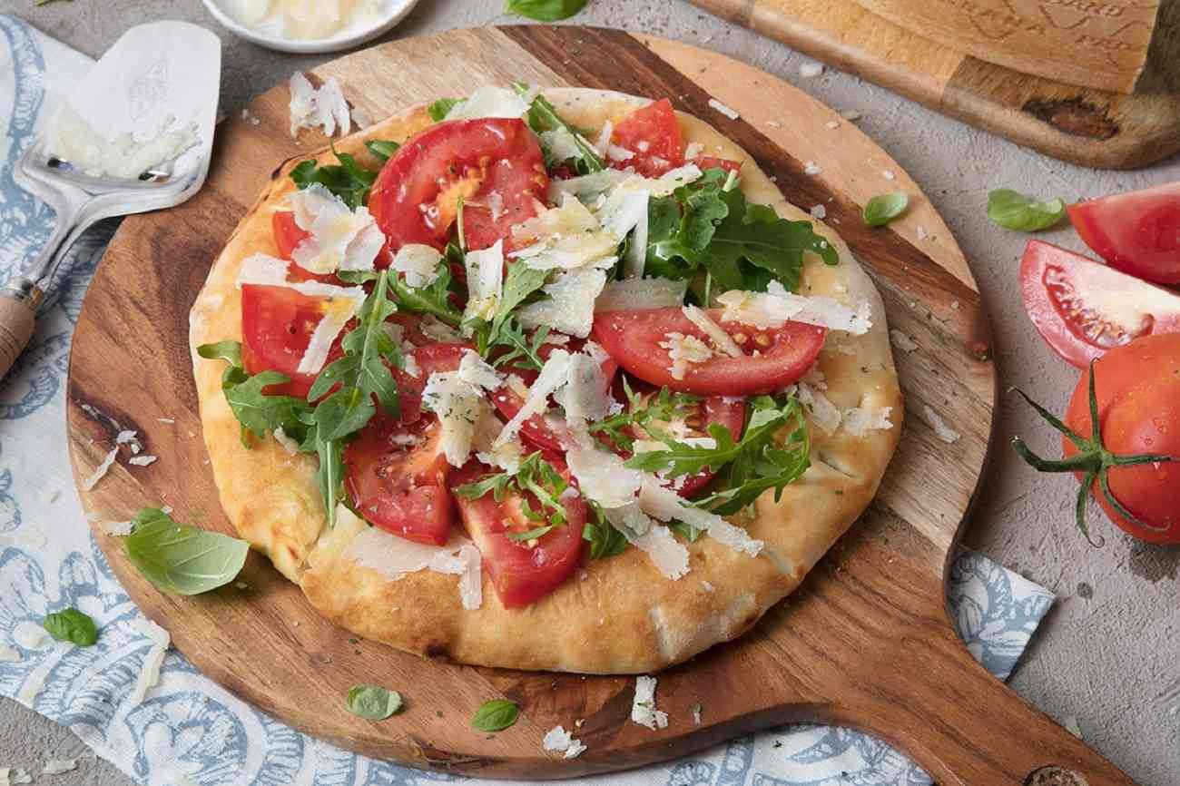 Pizza ohne Tomatensauce mit frischen Tomaten, Rucola und Splittern vom ...