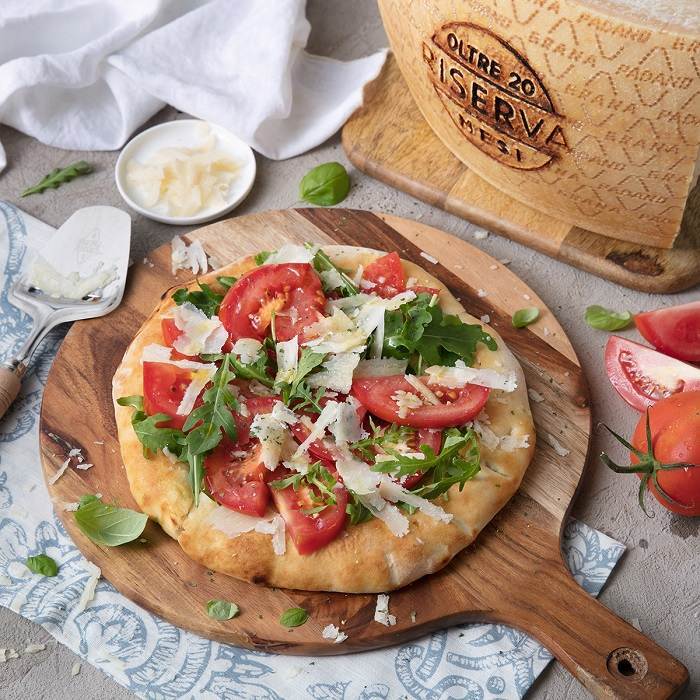 Pizza ohne Tomatensauce mit frischen Tomaten, Rucola und Splittern vom Grana Padano Riserva