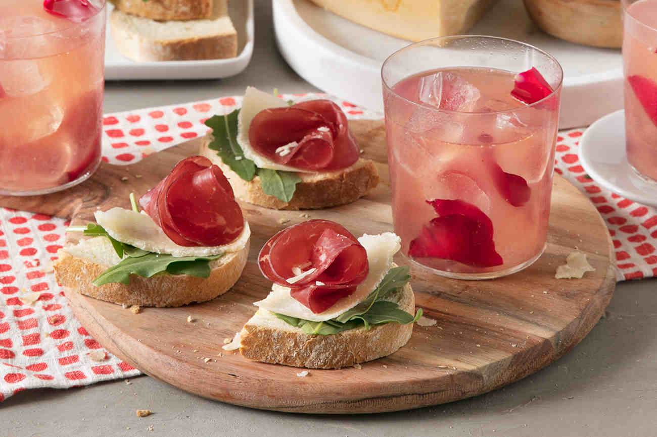 Spritzer accompagné de tartines de bresaola, roquette, citron et copeaux de Grana Padano