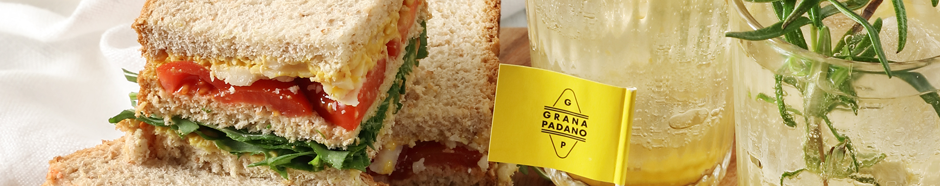 Analcolico-con-succo-di-ananas,-acqua-tonica,-zenzero-e-rosmarino-con-mini-tramezzini-di-pane-integrale,-pomodoro,-rucola,-senape-e-scaglie-di-Grana-Padano-m